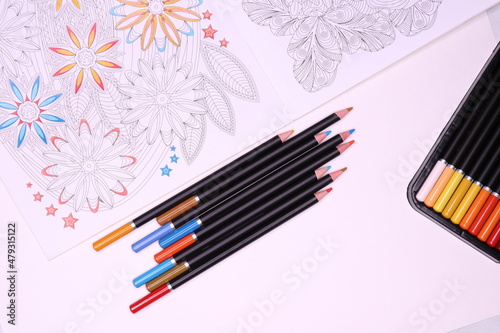 Colouring book antistress and colored pencils on white background.Top view.
