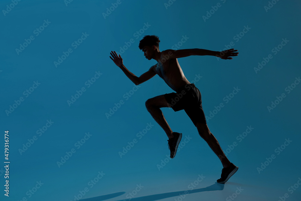 Concentrated sports man running on blue background