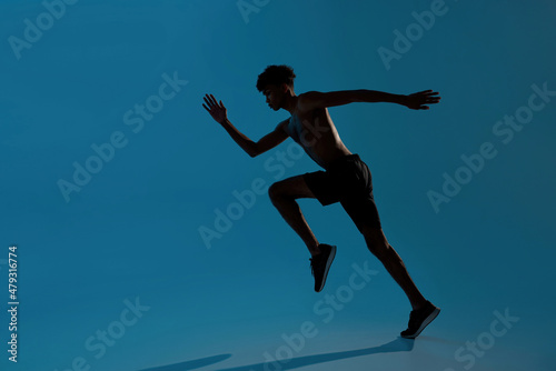 Concentrated sports man running on blue background © Svitlana
