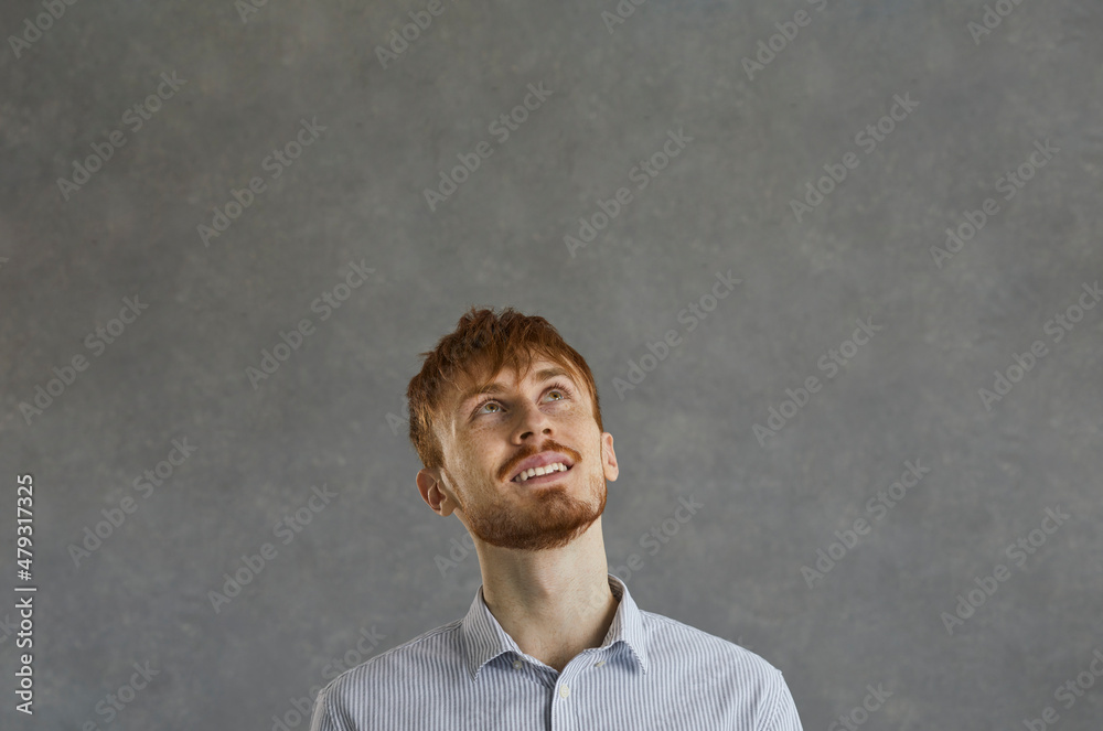 Headshot portrait of red-haired young hipster man freelancer or office worker looking up with dreaming expression on face. Daydreaming, future planning, wishing people emotion concept Headshot portrait of red-haired young hipster man freelancer or office worker looking up with dreaming expression on face. Daydreaming, future planning, wishing people emotion concept