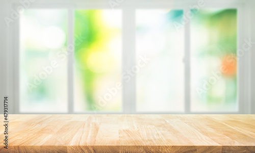 Empty wood table top on blur abstract green garden from window view.