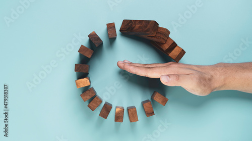 Fotografie Top view and flat lay design of Businessman use gesture to stop wooden domino circle falling for insurance assurance and risk management concept