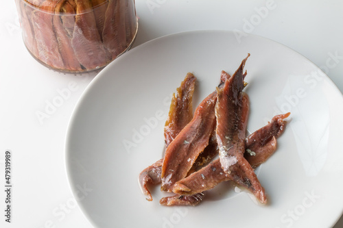Preserved bottle anchovy fillets on white plate - anchovies background