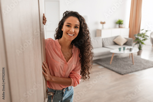 Photographie Cheerful young curly lady inviting people to enter home