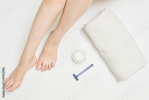 Woman legs with towel, razor and cosmetic cream, concept of skin care and hair removal from the legs © Marco