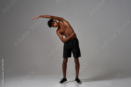 Black sportsman stretching and looking at camera