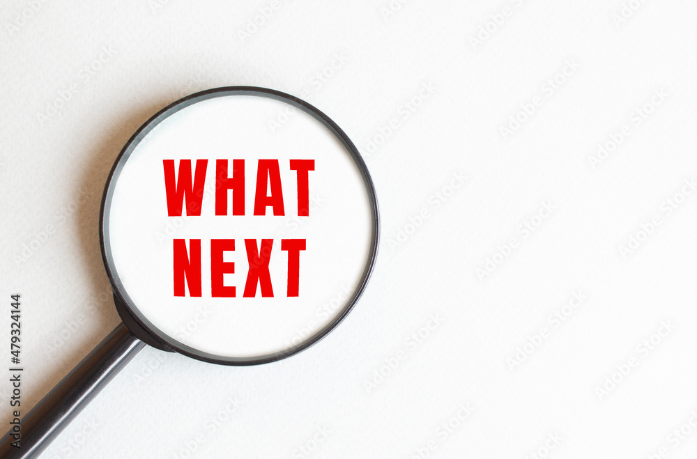 The text WHAT NEXT is written on a gray background. We read through a magnifying glass. The text WHAT NEXT is written on a gray background. We read through a magnifying glass.