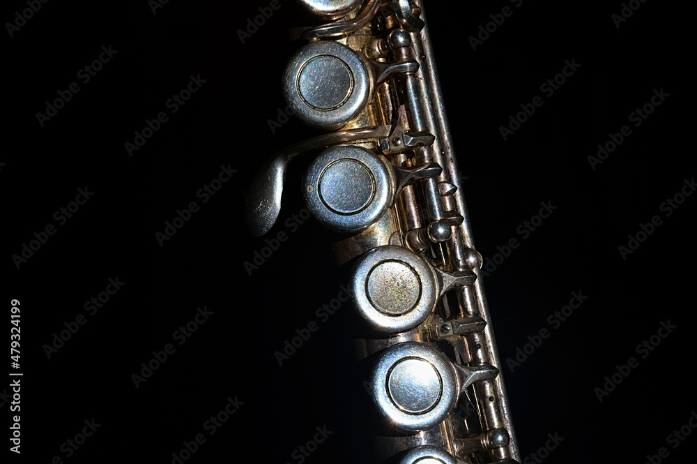 Fototapeta premium Detail of central part of older transverse flute, silver coated with visible signs of heavy use and corrosion, on dark background. 