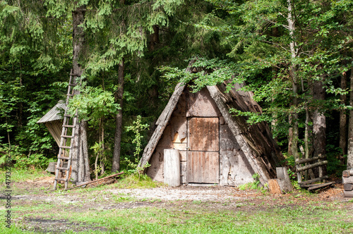 A small wooden hut in the woods serving as a storehouse for animals and feeders.