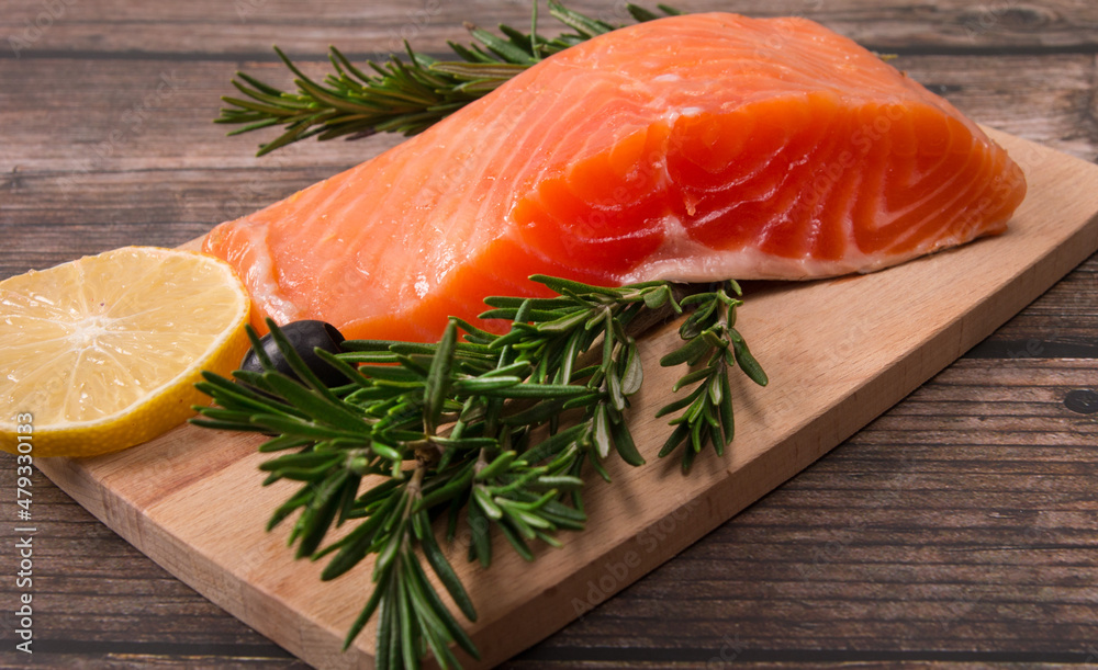 red salted fish on a cutting board with rosemary and lemon