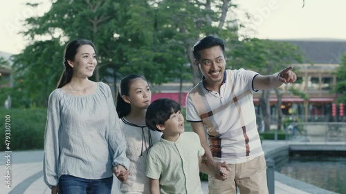 Asian family parents and kids walking on waterfront promenade