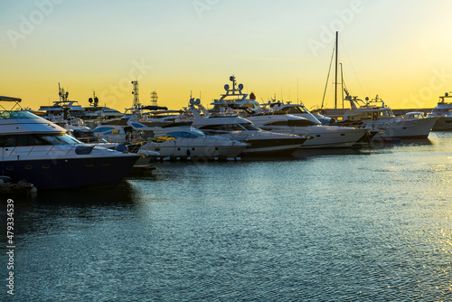 Luxury yachts docked in sea port at sunset. Marine parking of modern motor boats and blue water. Tranquility, relaxation and fashionable vacation © Aleksey Dmetsov