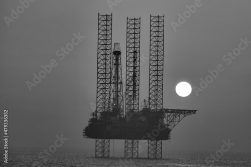 Black and white sunset view of oil drill