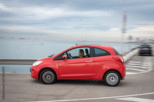 Young girl enjoying driving her little red car