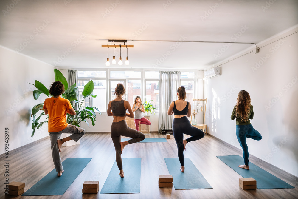 Man and women meditating in Tree pose Man and women meditating in Tree pose
