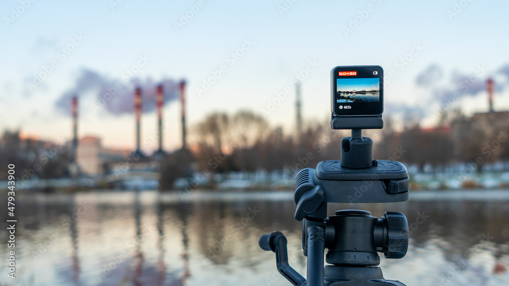 A small camera is filming an industrial plant. Defocused background with CHP pipes. Ecological concept. A small camera is filming an industrial plant. Defocused background with CHP pipes. Ecological concept.