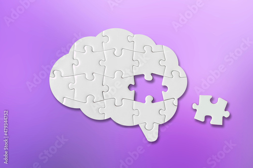 Brain shaped white jigsaw puzzle on purple background, a missing piece of the brain puzzle, mental health and problems with memory