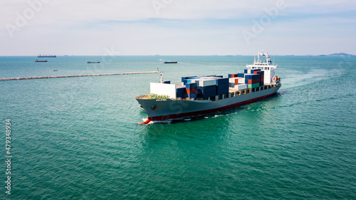 aerial in front view container ship and tugboat dragging floating in green sea, business and industry Transportation cargo logistics services of international by container ship in ocean