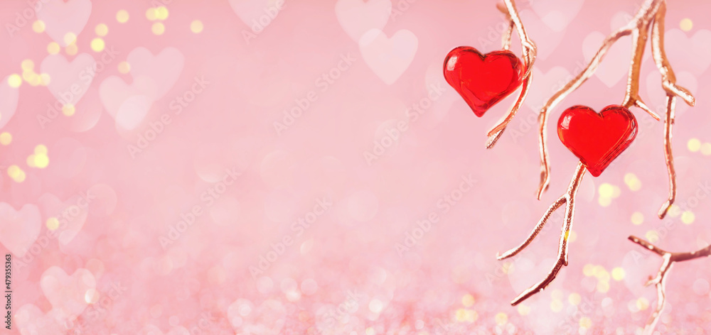 Two red glass hearts on golden branches with beautiful light. Love and date. St Valentines Day card. 14 February wedding invitation or thank you concept. Wide banner with copy space