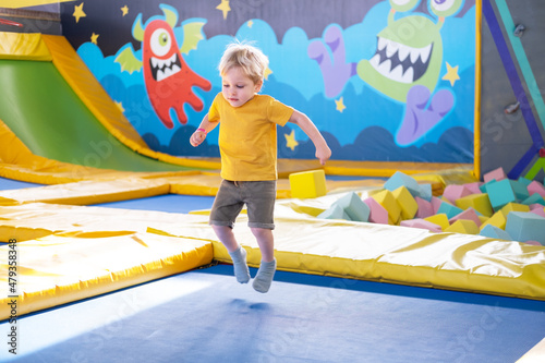 cute blond little boy jumps in a trampoline park, children activity