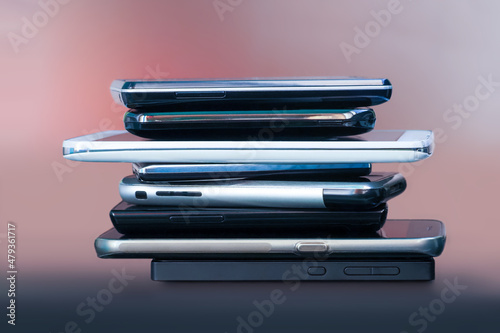 Mobile phones in stack on table. Set of contemporary smartphones, side view. Wireless communication technology and mobility concept, group of smartphones