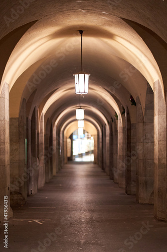 Urban lantern in a building avenue at night. Architecture with round vault and columns. Depth blur.