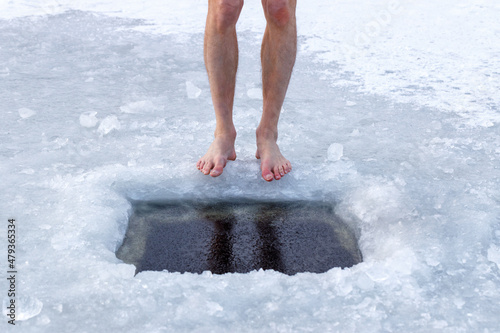 Health and cold water hardening. Man and ice hole. Legs and ice hole close-up.