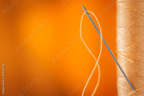Sewing supplies: sewing thread, large spool of thread, needles. Close up