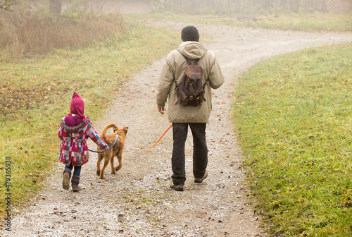 father child and dog walking in rain