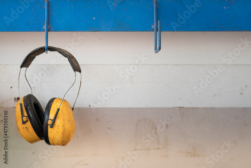An earmuff, the PPE which is use to protect loud noise in worker environment, its handing on the metal rack. Industrial working safety equipment object. Close-up. photo