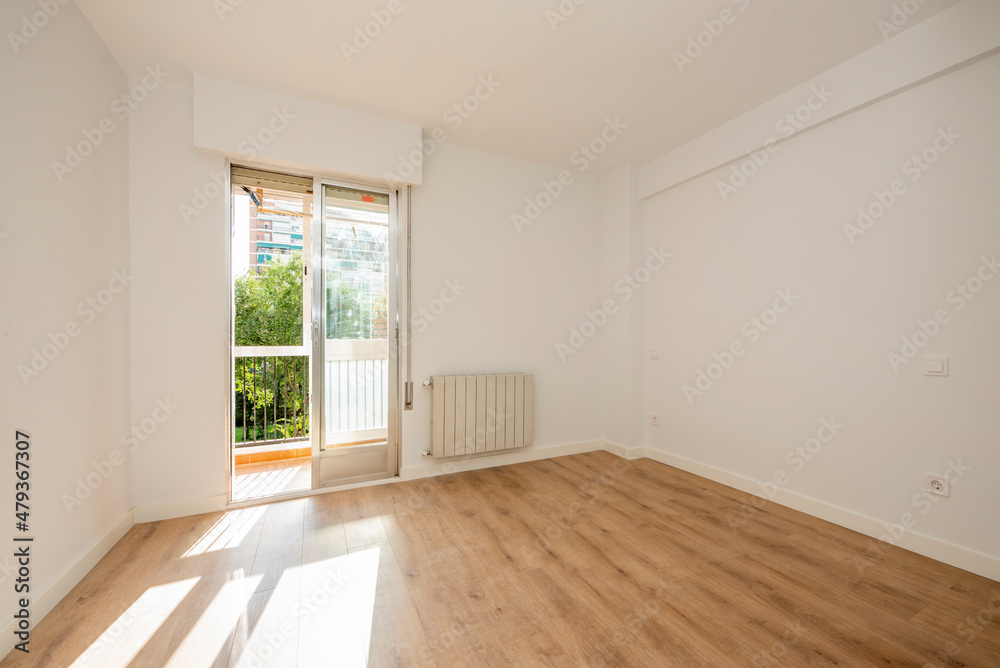 Empty living room with exit window to an urban terrace with parquet floors