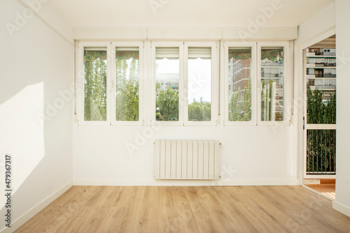 Fototapeta Naklejka Na Ścianę i Meble -  Living room with wall full of windows overlooking a patio with plants and trees