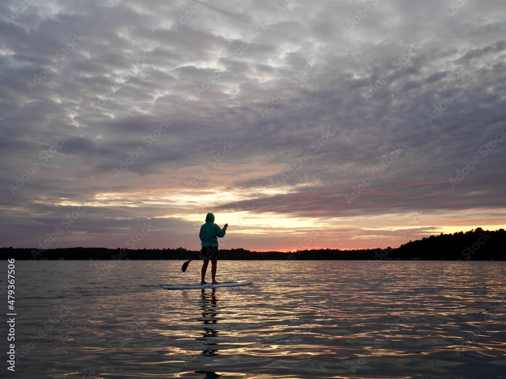 Stand up paddling on peaceful Big Trout Lake at sunrise. Minnesota, the Land of 10000 lakes, USA.