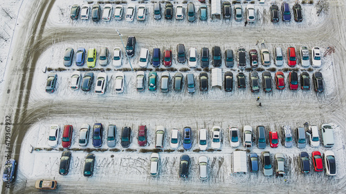 Aerial top view parked snow covered cars. Many snowy cars on the parking at the winter snowfall