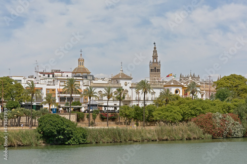 Green quay of Guadalquivir river in downtown sevilla, with Giralda tower and dome of the cathedral 