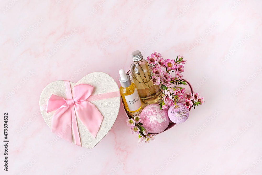 heart gift box with with spa treatments and pink flowers on pink marble background. festive spring season. 14 february, Valentine's day, romantic gift for women. top view. copy space