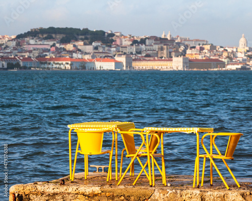 A vintage yellow restaurant table near the water looking out to Terreiro do Paço in Lisbon, Portugal photo