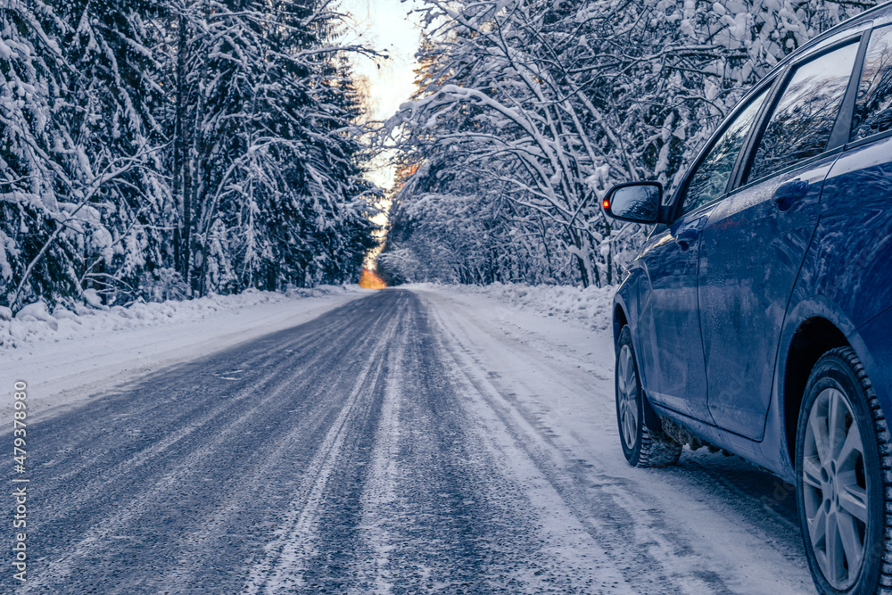 Car tires on a winter snow - covered forest road . Winter landscape with a blue car in the forest. Car tires on a winter snow - covered forest road . Winter landscape with a blue car in the forest.