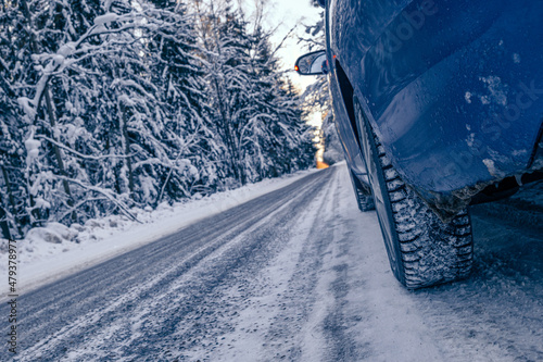 Car tires on a winter snow - covered forest road . Winter landscape with a blue car in the forest. © Sergey