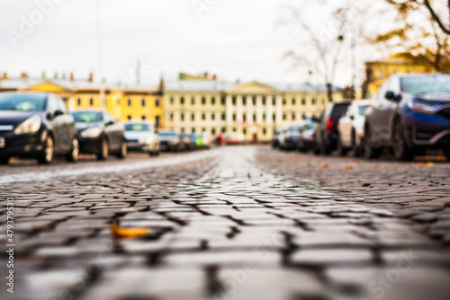 Autumn day in the city. The old pavement. The car is parked on the street. Focus on the stones. Close up view from the pavement level. © Georgii Shipin