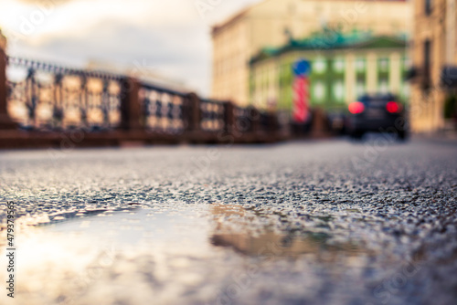Rainy day in the city. The car is driving along the road. Rainy day in the city. The road after the rain. Focus on the asphalt. Close up view from the asphalt level.