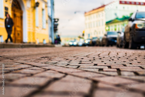 Cloudy autumn day in the city. Headlights of an approaching car. A pedestrian walks along the sidewalk. Historical center of the city. Close up view from the level of the pavement.