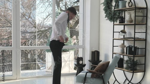 Man arriving late for work dresses in a hurry and speaks on the phone. Urgent call to work or service