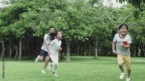 Asian father playing with kids in park chasing and laughing