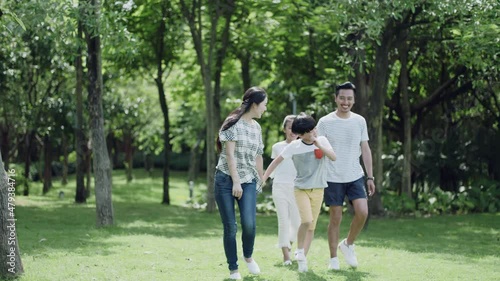 Asian family, parents and kids walking in green park