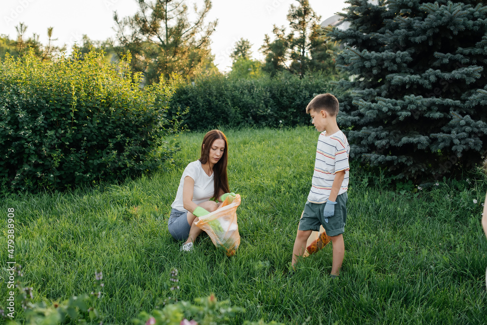 Mom and son are cleaning garbage in the park at sunset. Environmental care, waste recycling. Mom and son are cleaning garbage in the park at sunset. Environmental care, waste recycling.