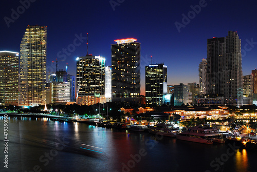 A boat cruises the Intercostal Waterway in front of the Miami Skyline at night © kirkikis