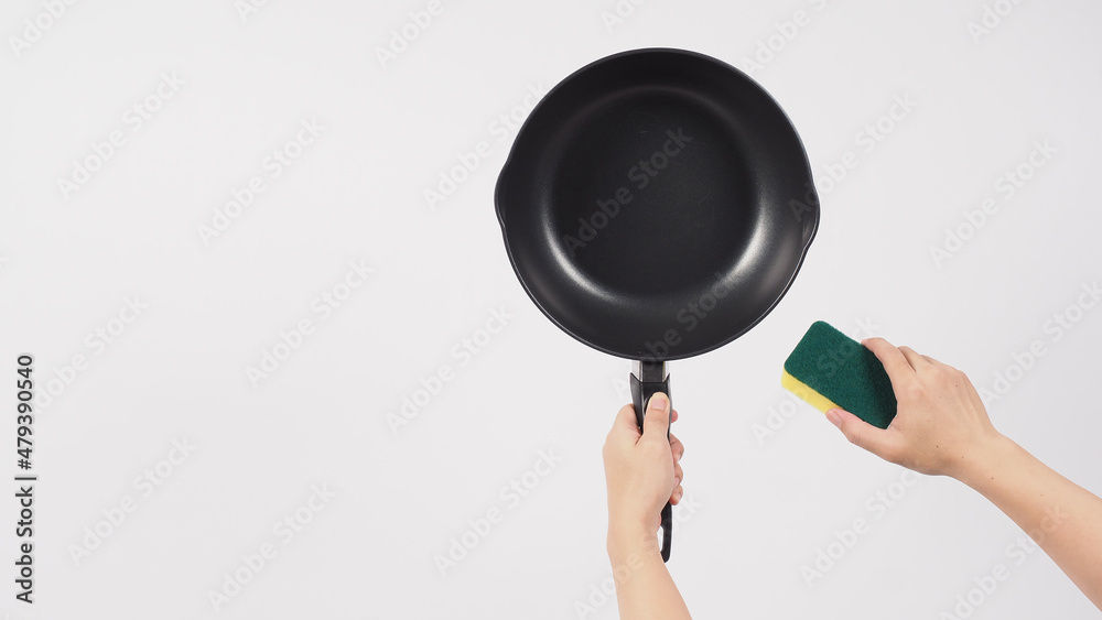 Cleaning Electric non stick pan. Hand on white background cleaning the non stick pan with handy dish washing sponge which yellow color on the soft side and green on hard side for hygiene after cook. Cleaning Electric non stick pan. Hand on white background cleaning the non stick pan with handy dish washing sponge which yellow color on the soft side and green on hard side for hygiene after cook.