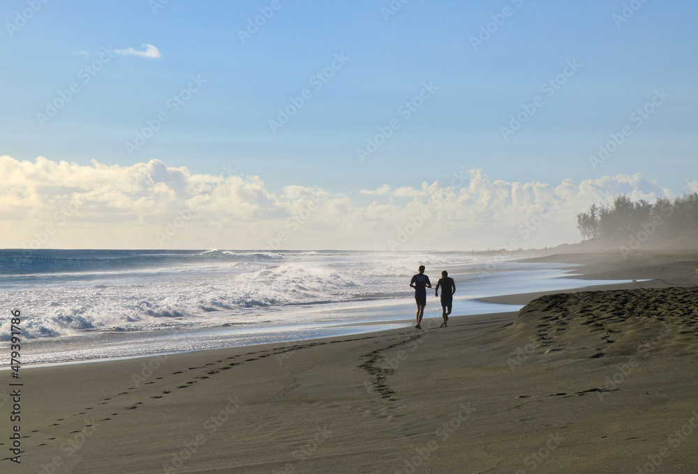running au coucher de soleil sur la plage de saint leu à la réunion au bord de l'océan indien  avec traces sur le sable 