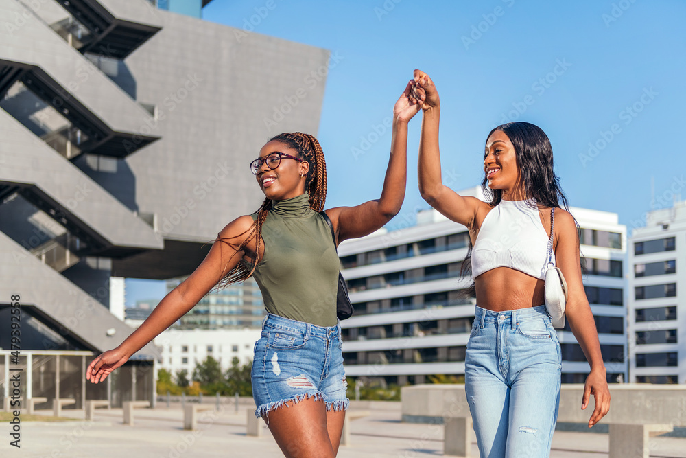 two young friends dance in the city holding hands